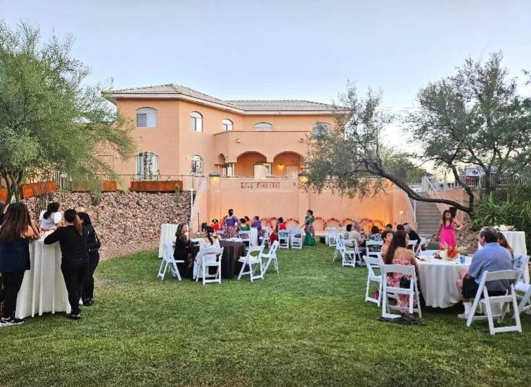 An outdoor evening event at Himaya Garden with guests seated at round tables on a green lawn.